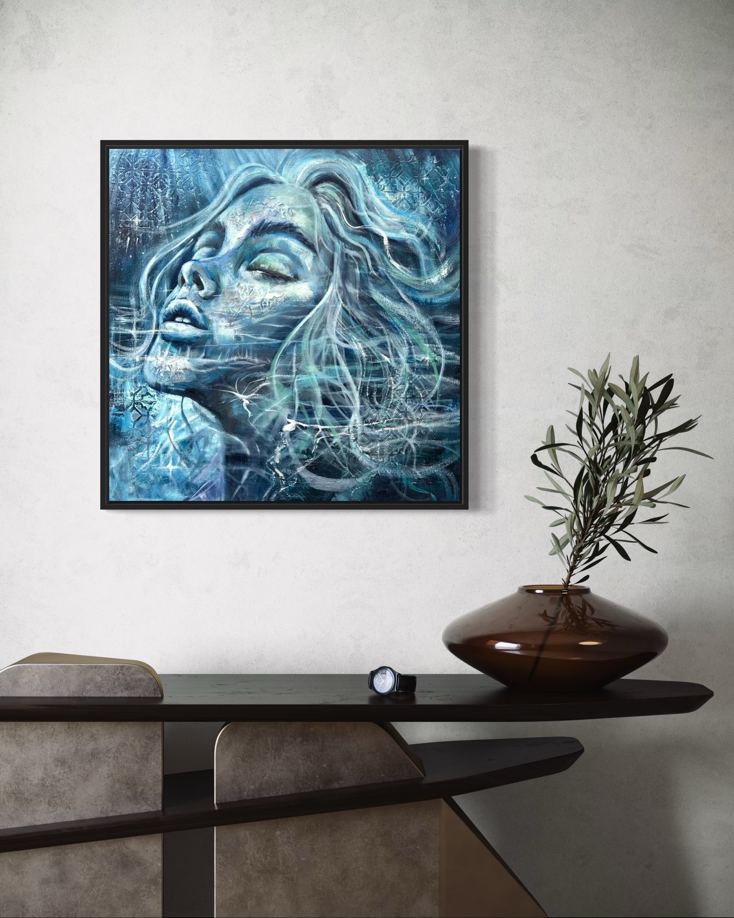 Framed abstract art of a woman's face on a wall above a console table with decorative items.