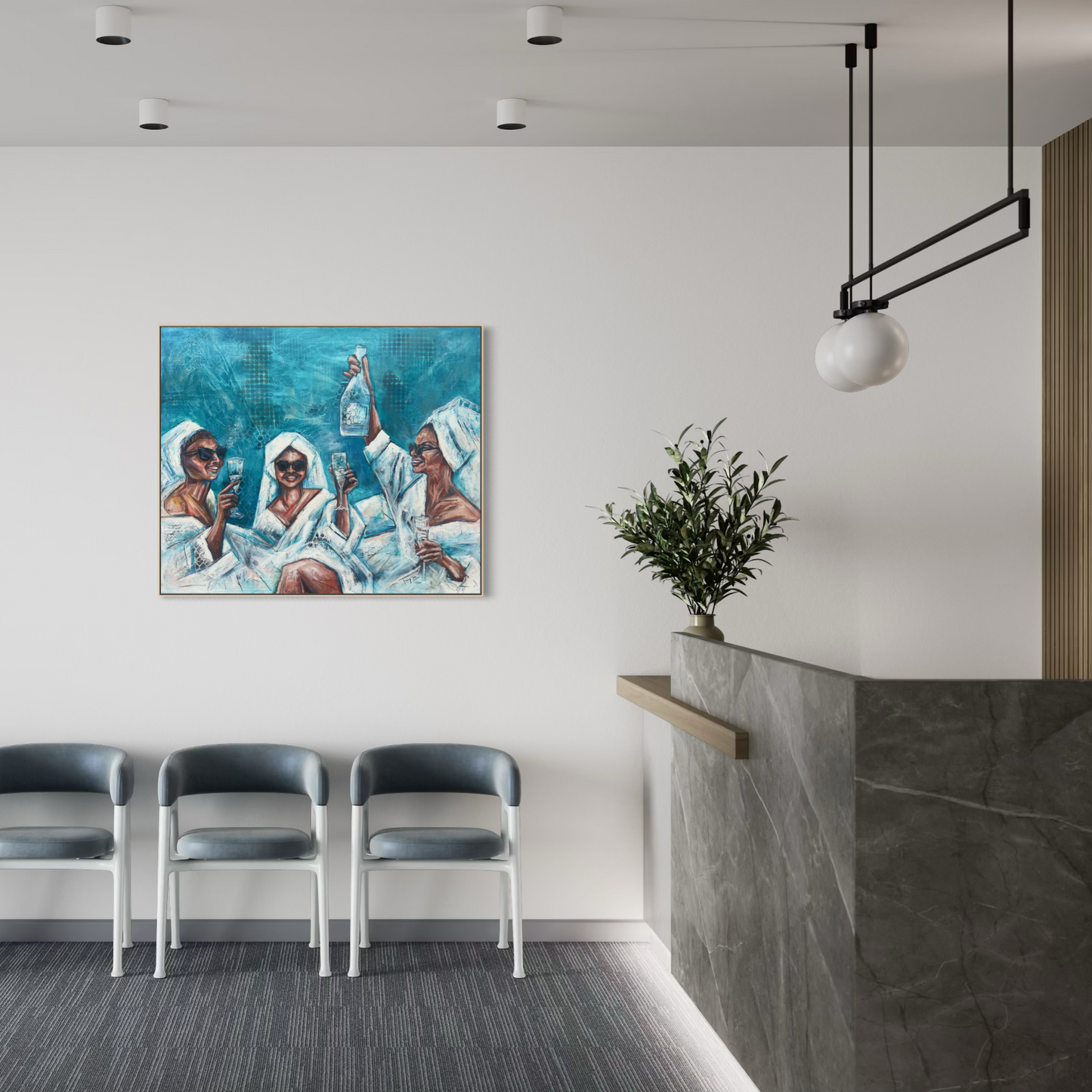 A framed painting depicting three figures in white robes against a blue background, displayed on a white wall in a modern office lobby with three gray chairs, a marble reception desk, and a hanging pendant light.