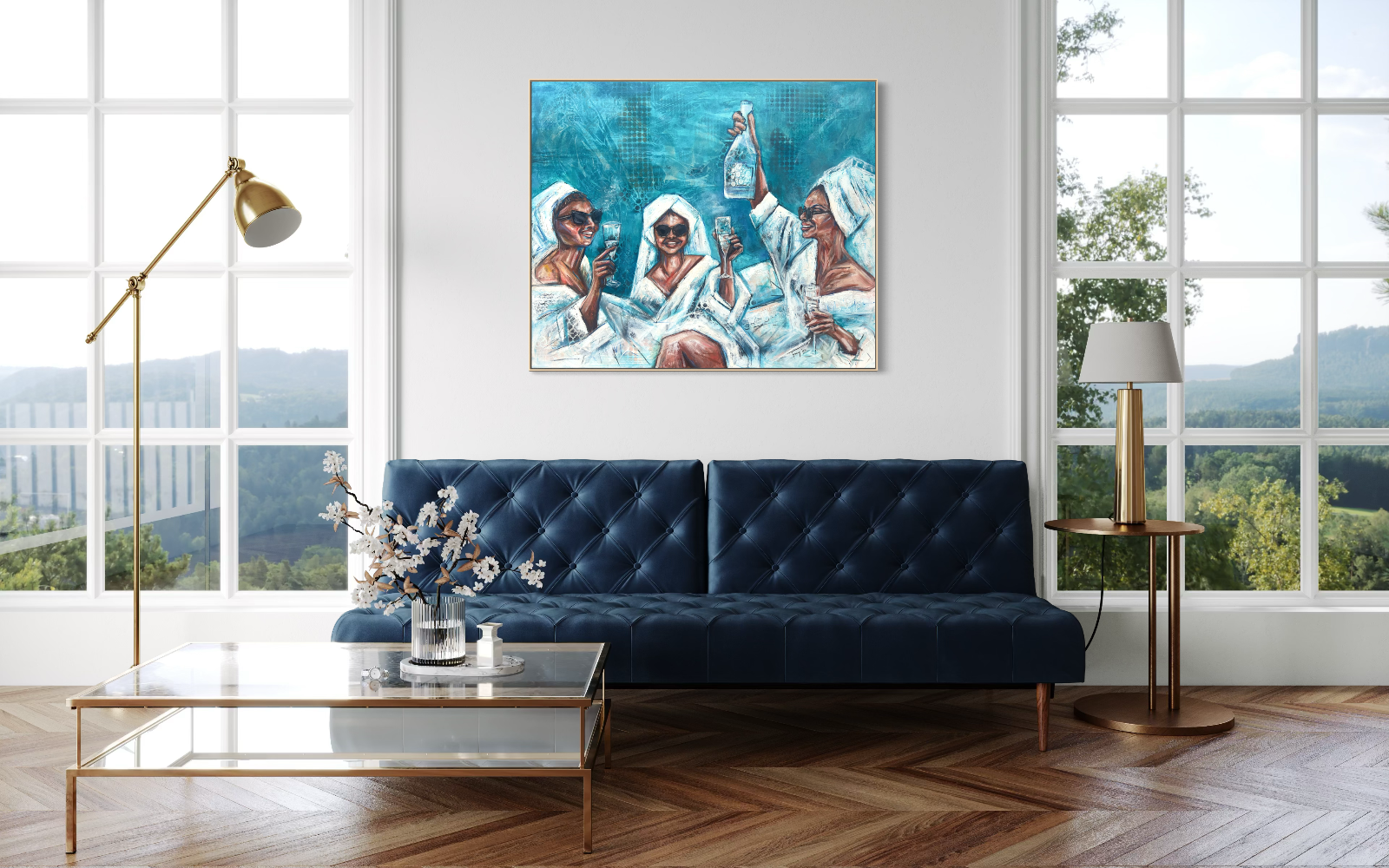 A framed painting of four women in white robes holding champagne glasses, displayed on a white wall above a navy blue tufted sofa in a modern living room with large windows, a gold floor lamp, and a glass coffee table.