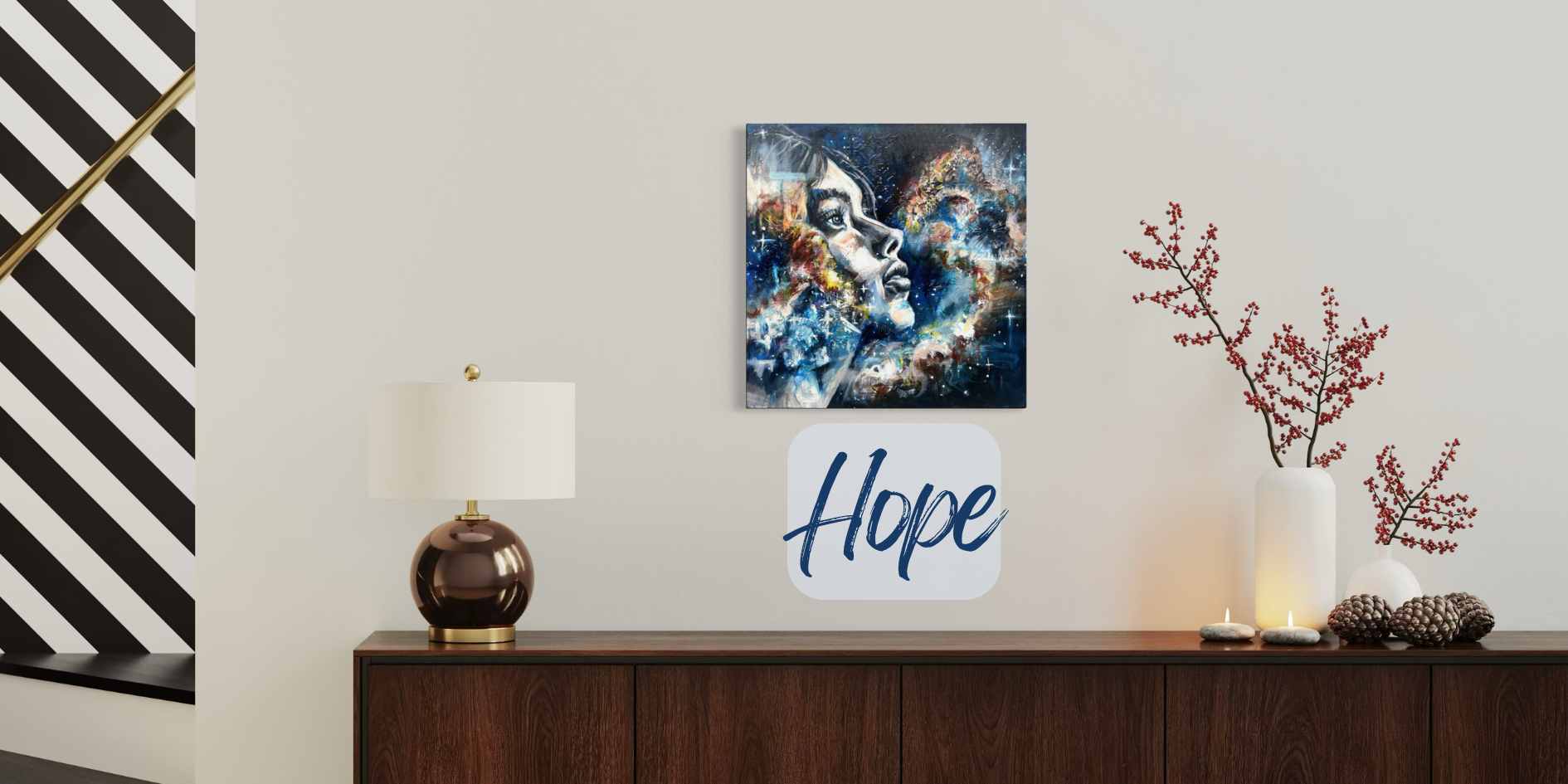 A square wall art piece showing a glowing angel with a sword, displayed in a styled room above a dark wood console table with a lamp, candles, and decorative branches. A white sign reading 'Hope' hangs below the artwork.