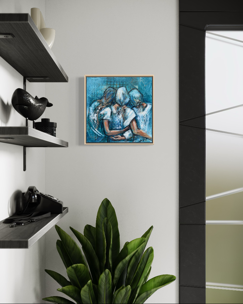 A framed square painting featuring three figures in blue and white tones, displayed on a light gray wall in a modern interior setting with floating shelves, decorative objects, and a green plant.