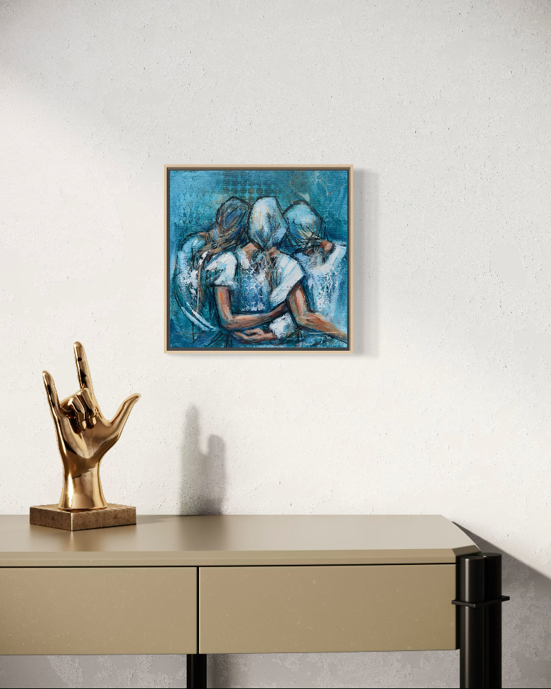 A framed abstract painting of three figures in blue tones hangs on a textured white wall above a beige console table with a gold hand sculpture.