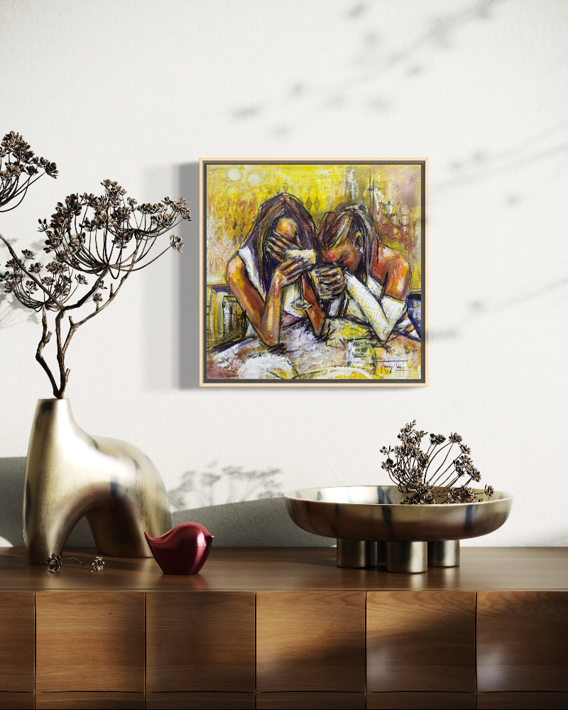 A framed painting of two women laughing, displayed on a white wall above a wooden console table with decorative vases and bowls.