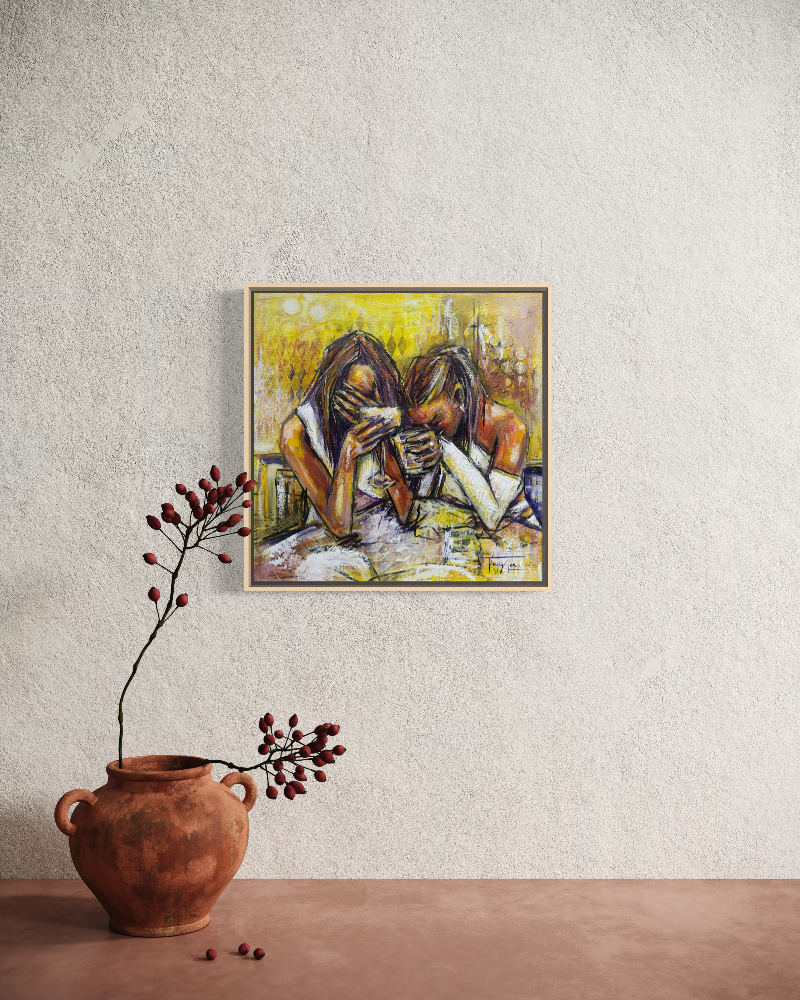 A framed painting of two women sitting and covering their faces, displayed on a textured off-white wall above a terracotta table with a rustic brown vase holding dried red berries.