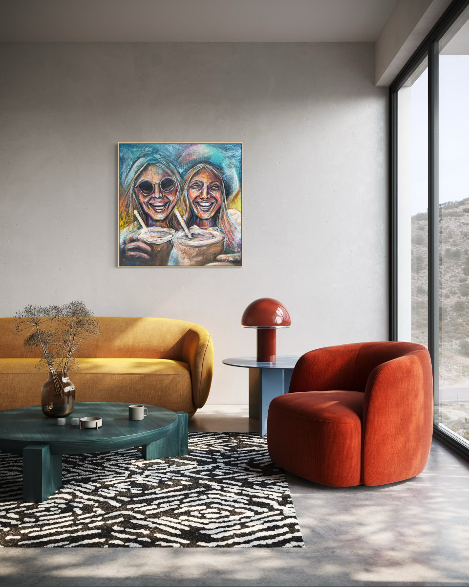 A colorful canvas painting of two smiling women holding cups, displayed on a light gray wall in a modern living room setting with a yellow sofa, red armchair, and teal coffee table.