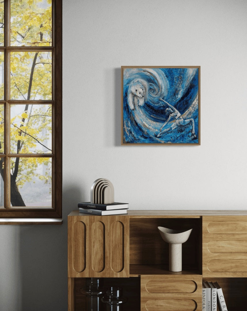 A painting featuring a stylized depiction of a woman and a polar bear against a blue background with swirling patterns. The woman appears to be in a warrior pose, and the polar bear is facing her. The painting is featured in a modern white scene with a wooden shelf and modern decorative features. The painting is framed in wood.