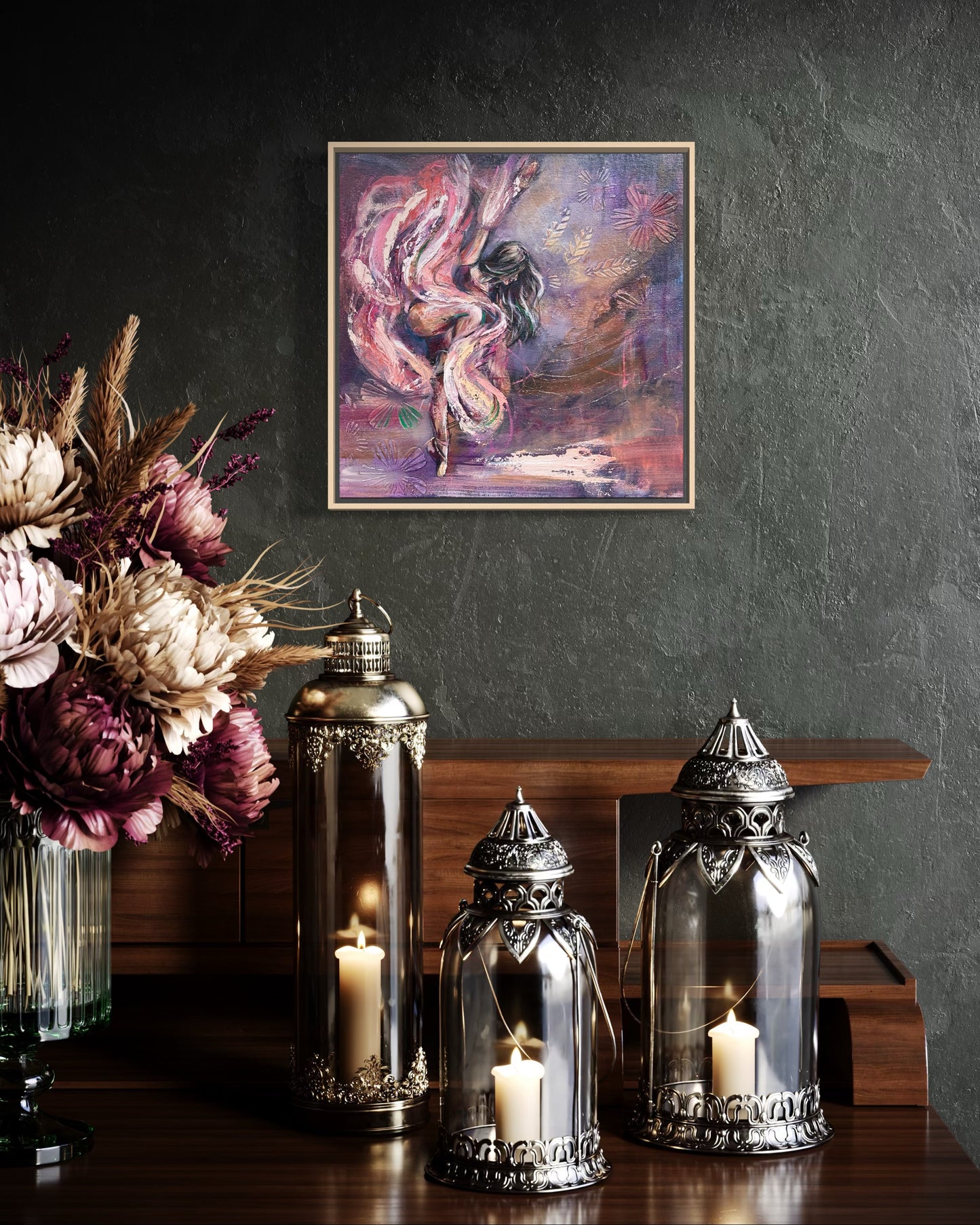 Decorative setup with candles in glass lanterns, flowers, and a framed painting of a dancer on a dark wall.