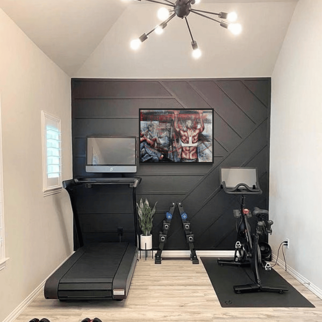 a modern home or hotel gym with treadmill, bike and weights with black wall features the painting "Stronger Than Yesterday" a painting of power perseverance and support and pushing your limits with strength and determination.