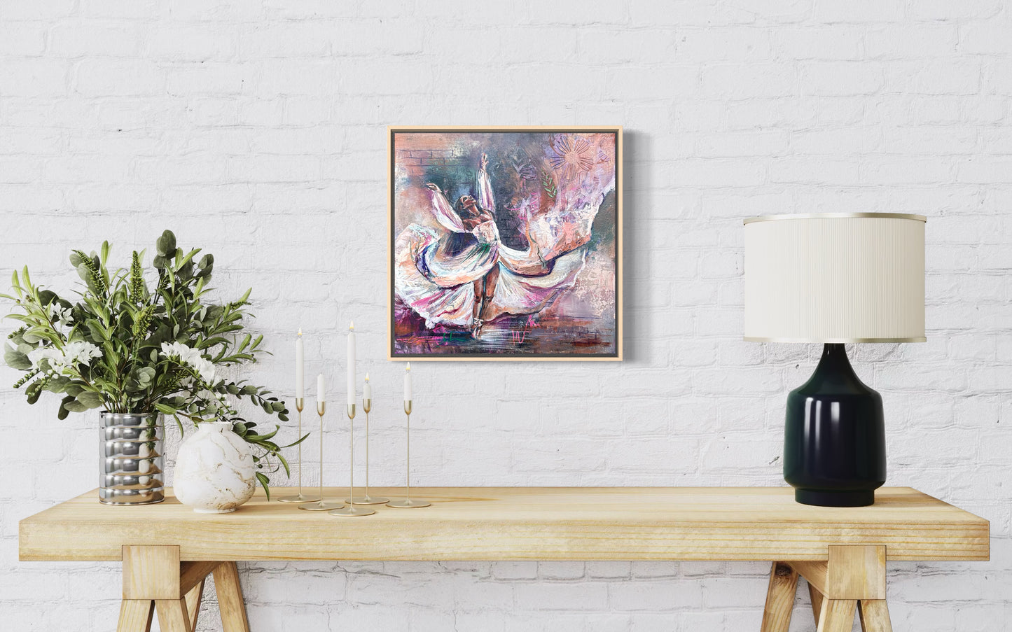 Framed abstract painting on a wall above a wooden table with decor items. Painting of dancer with flowing dress and arms and abstract elements.