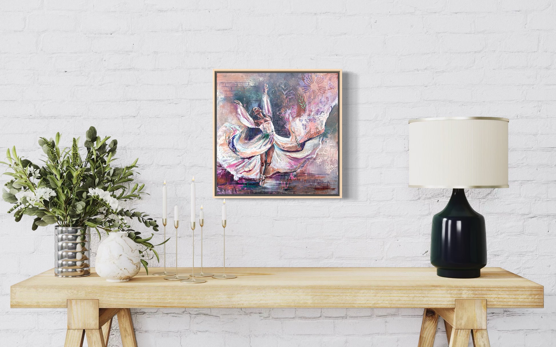 Framed abstract painting on a wall above a wooden table with decor items. Painting of dancer with flowing dress and arms and abstract elements.