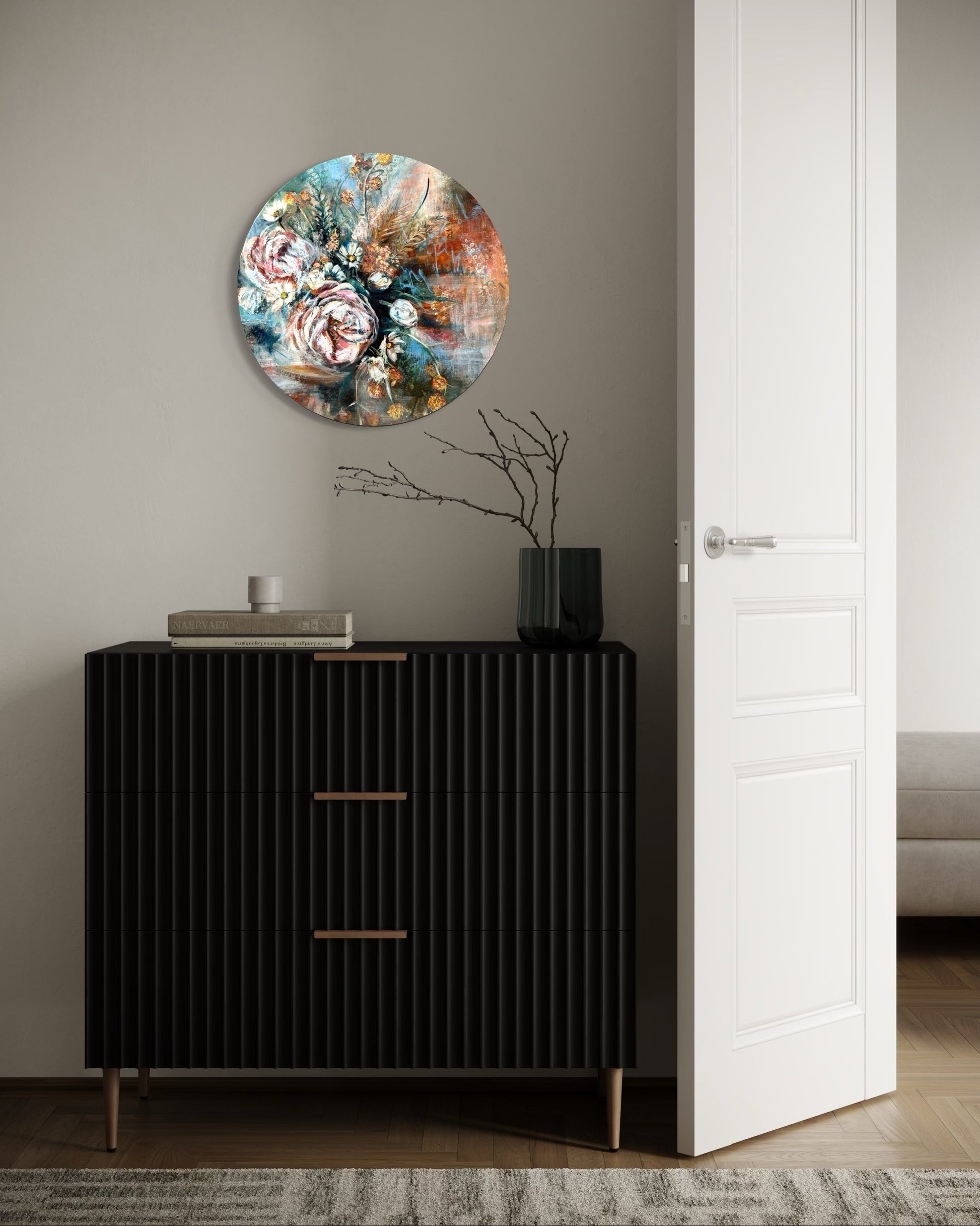 Round floral painting on a wall above a black cabinet with a white door.